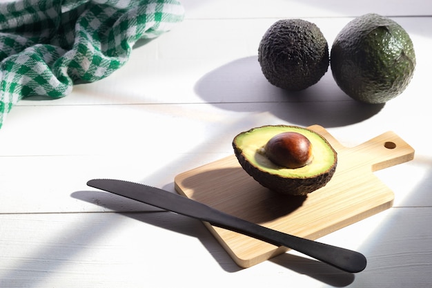 Composizione con avocado freschi su base in legno bianco.