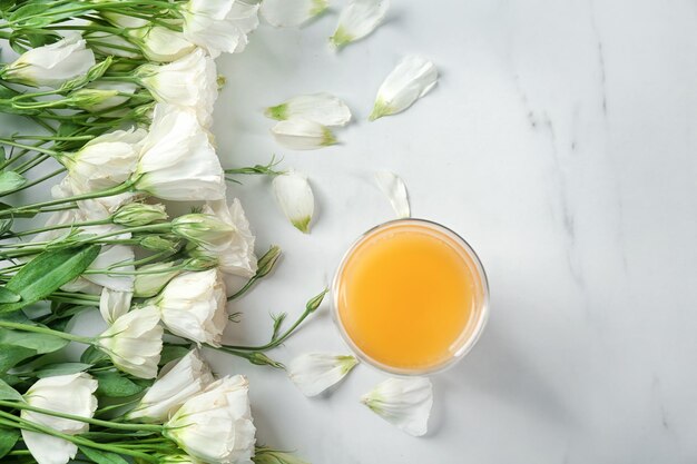 Composizione con bellissimi fiori e bicchiere di succo d'arancia su sfondo chiaro