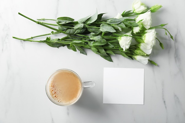 Composizione con bellissimi fiori e tazza di caffè in vetro sul tavolo