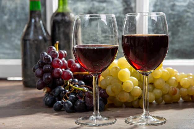 Composizione con bicchieri di vino, uva e bottiglie di vino rosso