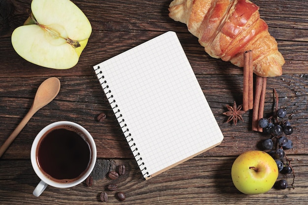 Composizione con caffè, blocco note e frutti diversi su un tavolo di legno scuro, vista dall'alto