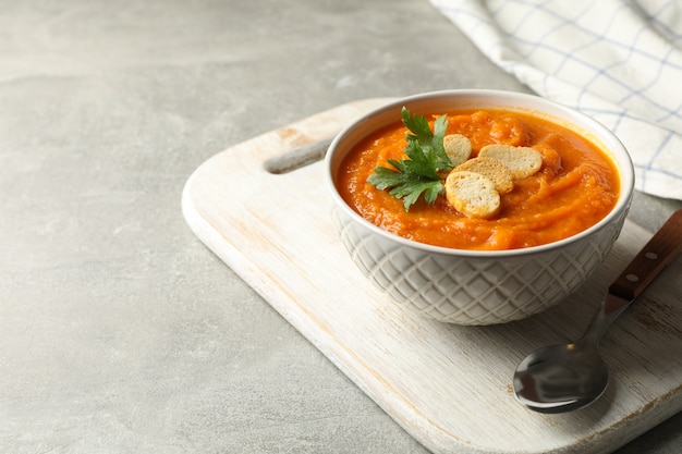 Composizione con ciotola di purea di zucca con crostini di pane sul tavolo grigio