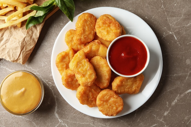 Composizione con crocchette di pollo, patate e salse sul tavolo grigio