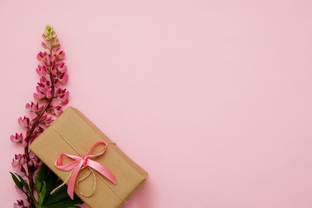 Composizione con fiori e regalo sul rosa