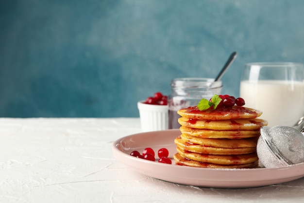 Composizione con frittelle con marmellata e mirtillo rosso sul tavolo bianco