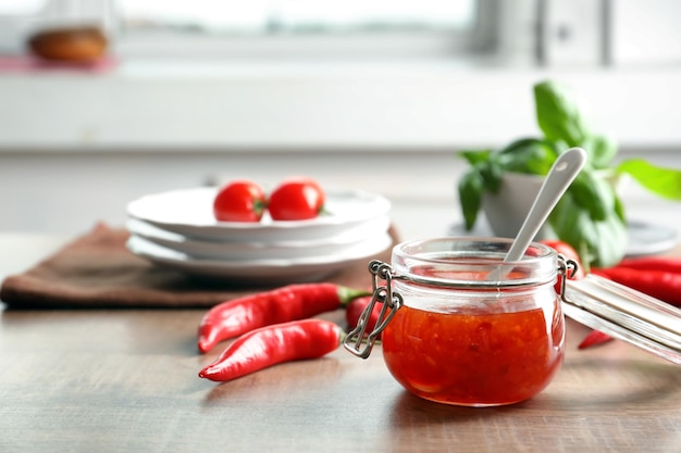 Composizione con gustosa salsa di peperoncino in barattolo sul tavolo