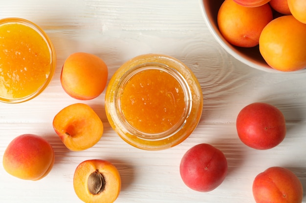 Composizione con gustose albicocche e marmellata sul tavolo di legno bianco