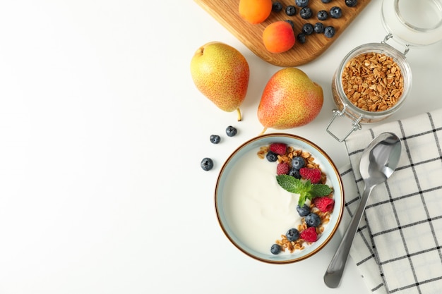 Composizione con il dessert e gli ingredienti del yogurt su fondo bianco