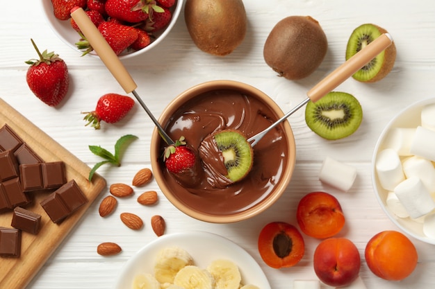 Composizione con ingredienti per fonduta di cioccolato su fondo di legno bianco. Fonduta di cottura