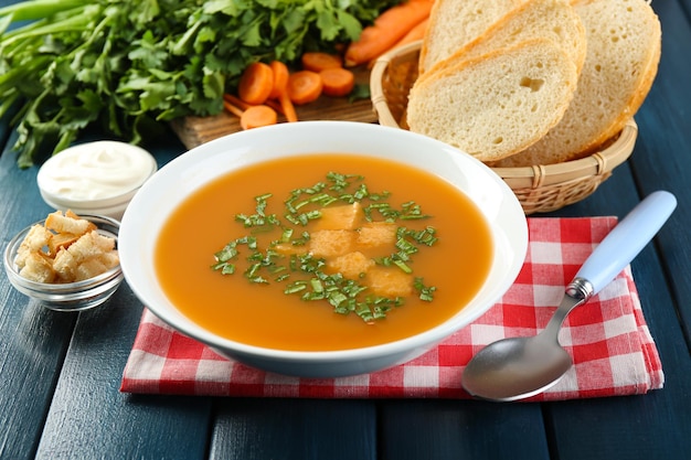 Composizione con ingredienti zuppa di carote ed erbe su fondo di legno di colore