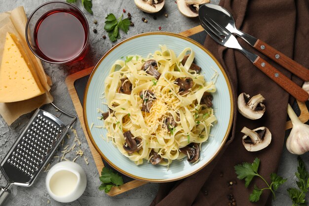 Composizione con la zolla di pasta saporita e gli ingredienti per la cottura sul gray