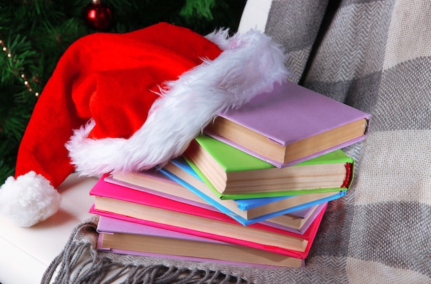 Composizione con libri e plaid, cappello rosso, su sedia sullo sfondo dell'albero di Natale