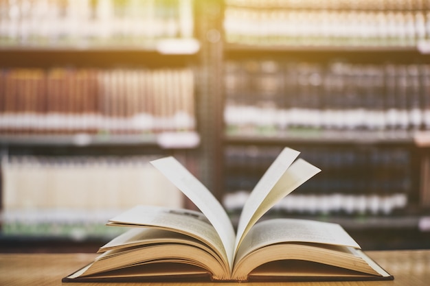 Composizione con libri, sul tavolo di ponte in legno e sullo sfondo di scaffale di libro.