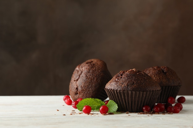 Composizione con muffin al cioccolato e frutti di bosco sul tavolo di legno bianco