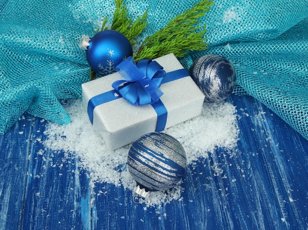 Composizione con palline di Natale, confezione regalo e neve su fondo in legno colorato