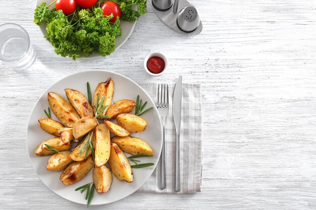 Composizione con piatto di deliziose patate al rosmarino sul tavolo