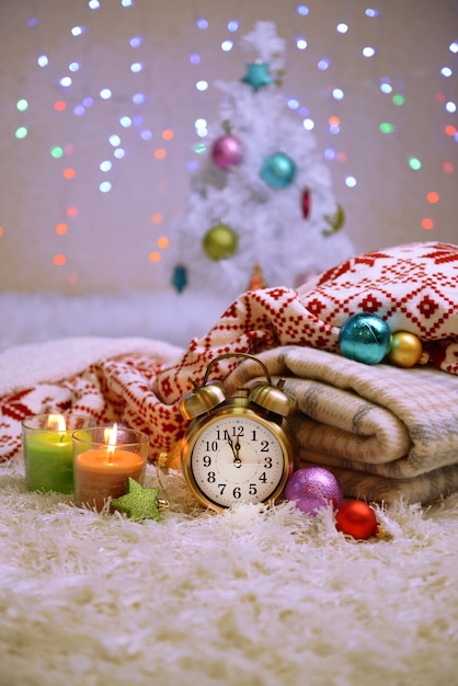 Composizione con plaid, candele e decorazioni natalizie, su tappeto bianco su sfondo luminoso
