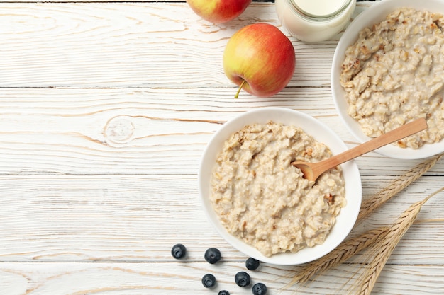 Composizione con porridge di farina d'avena su bianco in legno. Cucinare la colazione