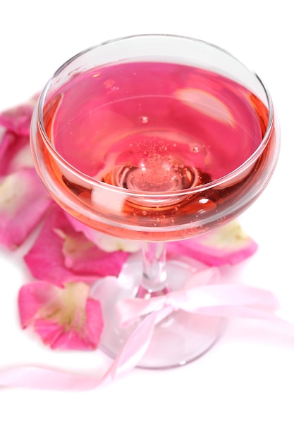Composizione con spumante rosa in vetro e petali di rosa isolati su bianco