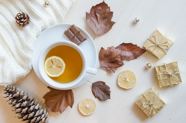 Composizione con tè, foglie, coni, limone e maglione lavorato a maglia.