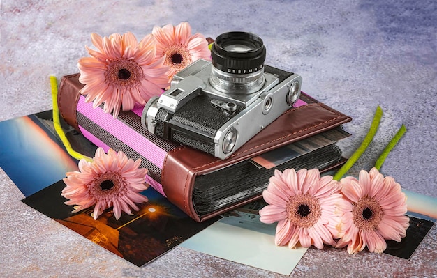 Composizione con una vecchia macchina fotografica un album fotografico foto a colori e fiori di gerbera rosa