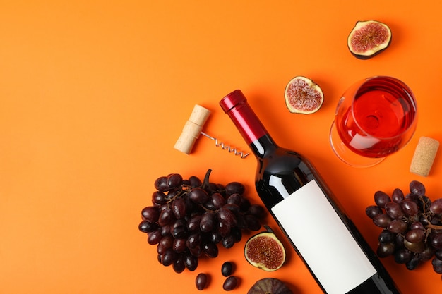 Composizione con vino, fichi e uva su sfondo arancione, vista dall'alto
