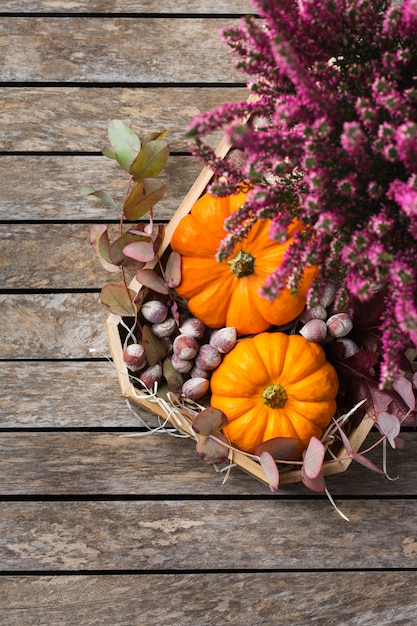 Composizione creativa del giorno del ringraziamento autunnale autunnale con zucche arancioni decorative ed erica viola. Lay piatto, vista dall'alto, copia spazio, sfondo in legno di natura morta. Concetto floreale e botanico.