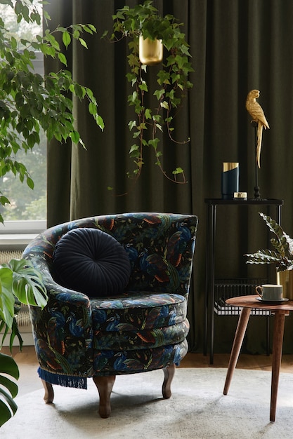 Composizione creativa dell'interior design del soggiorno con poltrona progettata, tavolino in legno, piante e accessori dorati. Concetto di giungla urbana. Modello.