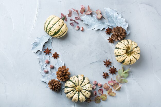 Composizione creativa di giorno di autunno di autunno di inverno di Natale con le foglie secche decorative e le zucche bianche. Disposizione piana, vista dall'alto, copia spazio, sfondo pastello blu natura morta per biglietto di auguri