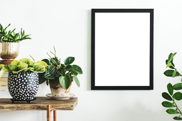 Composizione creativa di interior design per la casa con cornice per poster mock up, consolazione in legno, piante in vasi e accessori dal design hipster. La natura e le piante amano i concetti.