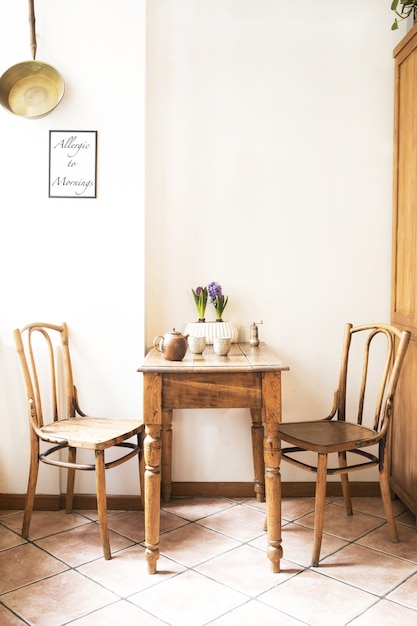 Composizione creativa di interni accoglienti ed eleganti della sala da pranzo con tavolo, sedie, piante e accessori. Locale soleggiato e luminoso. Colori neutri. Pareti beige.