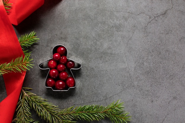 Composizione creativa di rami di albero di Natale e cookie cutter con bacche rosse