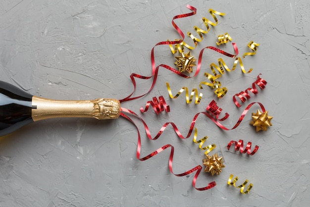 Composizione creativa piatta con bottiglia di champagne e spazio per il testo su sfondo colorato Bottiglia di champagne con festa colorata di stelle filanti o concetto di Natale