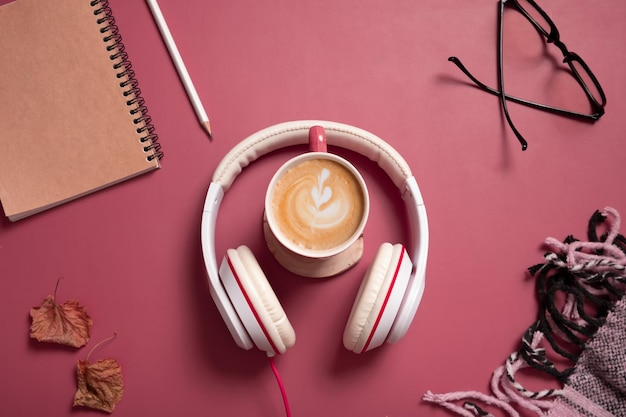 Composizione creativa piatta con tazza di caffè e cuffie su sfondo di colore rosa scuro Musica creativa relax concetto online
