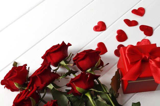 Composizione da un mazzo di bellissime rose rosse, confezione regalo sullo sfondo. Regalo di San Valentino.