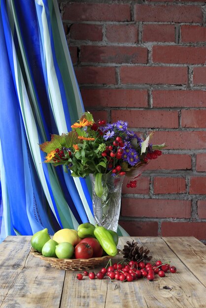 Composizione da un piatto con frutta e verdura in un vaso con piante autunnali