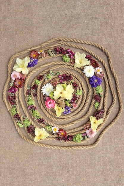 Composizione decorativa su tela con corda e fiori vari.