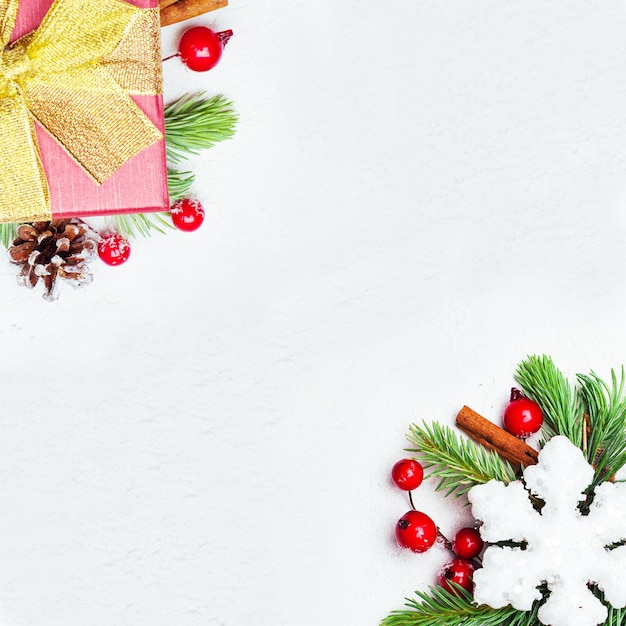 Composizione del bordo del fondo della cartolina di Natale con il ramo verde dell'abete di Natale, le bacche rosse dell'agrifoglio e le bagattelle su fondo bianco