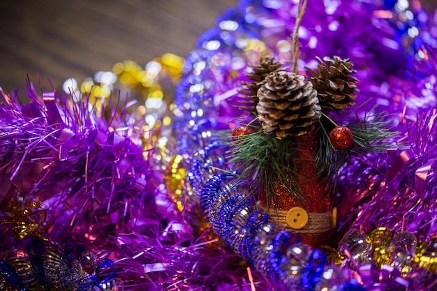 Composizione del primo piano delle feste di Natale con il cono rosso del giocattolo nel mucchio colorato della canutiglia con il fuoco selettivo