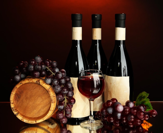 Composizione della botte di legno del vino e dell'uva su sfondo rosso scuro