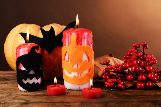 Composizione della candela della zucca e delle decorazioni di Halloween sulla tavola di legno su fondo di colore scuro