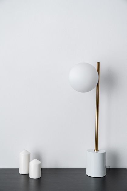 Composizione della lampada da tavolo alla moda dell'oro che sta sulla cima di legno nera con fondo bianco