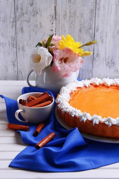 Composizione della torta di zucca fatta in casa sul piatto e fiori in vaso su uno spazio di legno