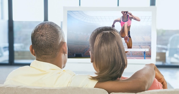 Composizione della vista posteriore di una coppia di appassionati di sport seduti sul divano a guardare un evento di atletica leggera in tv