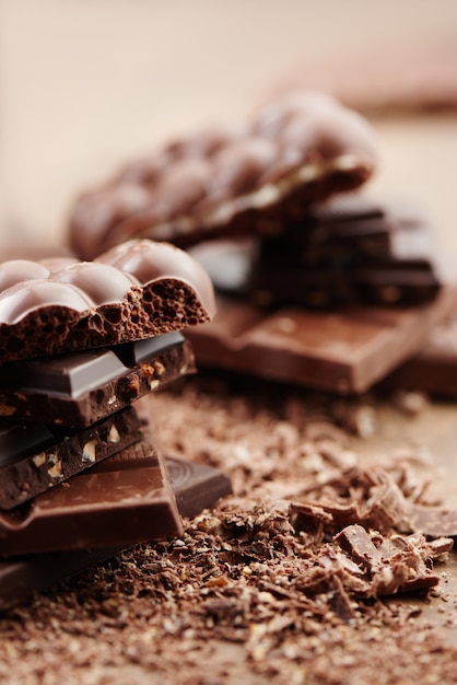 Composizione di barre e pezzi di latte diverso e cioccolato fondente, cacao grattugiato su una vista laterale sfondo marrone da vicino