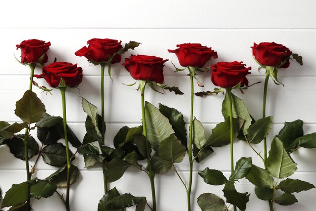 Composizione di bellissime rose rosse su fondo in legno