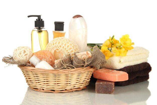Composizione di bottiglie di cosmetici e sapone in cesto isolato su bianco