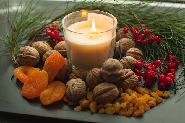 Composizione di candele di capodanno con ramo di abete e pasto sano. Il vassoio di Natale ha servito noci di candela