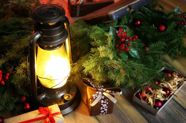 Composizione di Capodanno di rami di alberi di Natale decorati con palline Lampada vintage con candele accese e scatole piene di regali