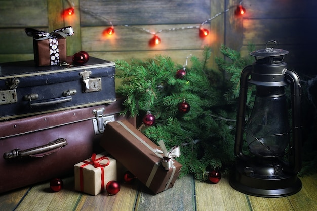 Composizione di Capodanno di rami di alberi di Natale decorati con palline Lampada vintage con candele accese e scatole piene di regali
